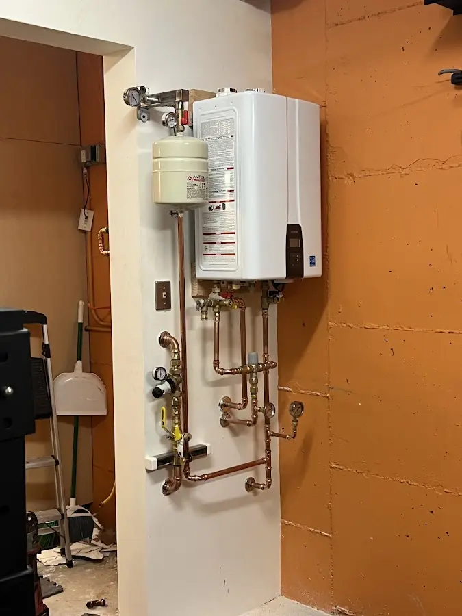 Plumbing technician inspecting water heater connections in Leoni